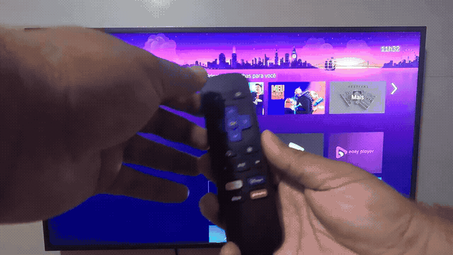 Mãos abrem a tampa e retiram as pilhas do controle Roku Express